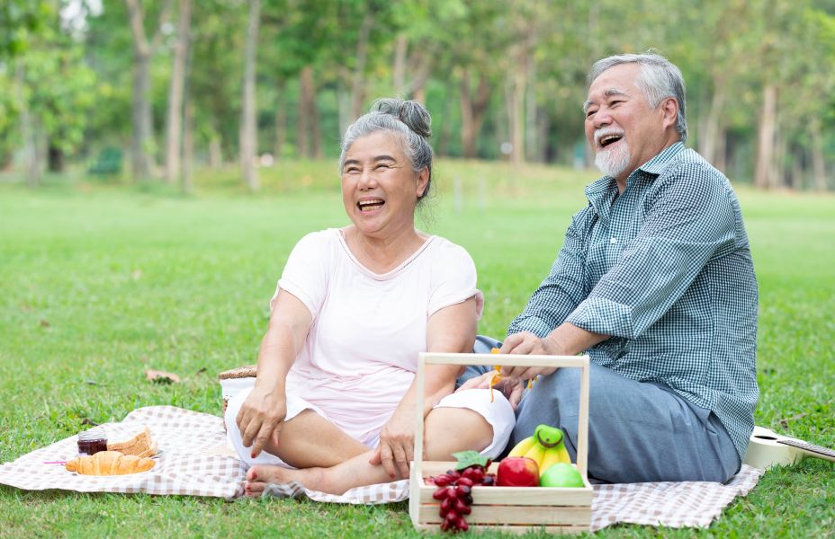 older couple sitting on a picnic blanket in the park